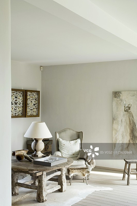 动物皮地毯上的乡村实木桌子，旁边是古董翼背椅和绘画图片素材
