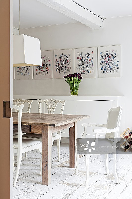 用餐区内的木桌、白色椅子、白色餐具柜和现代艺术，配有复古木地板图片素材