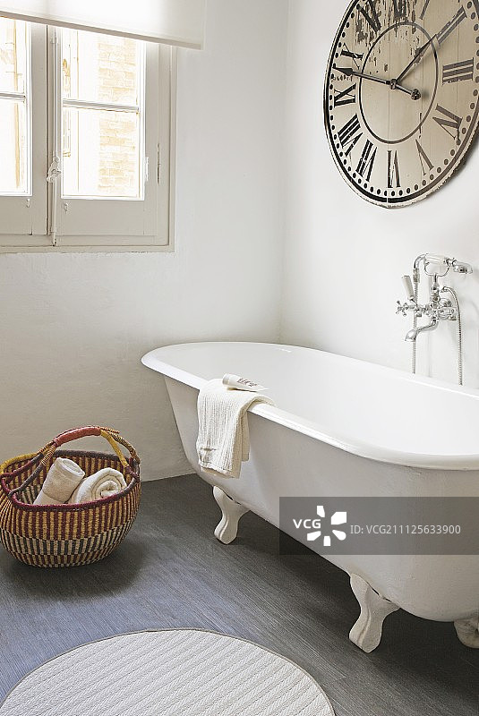 浴室中的独立式浴缸和大型复古时钟图片素材