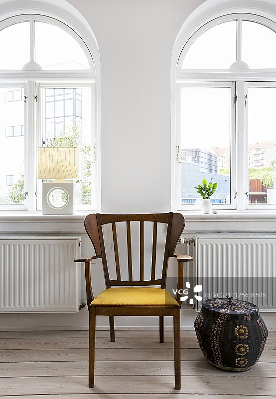 翻新公寓中拱形窗户前的异域木扶手椅和民族风柳条筐图片素材