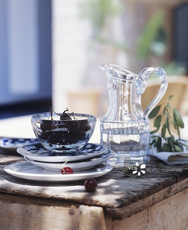 乡村木桌上的水罐和一碗樱桃图片素材