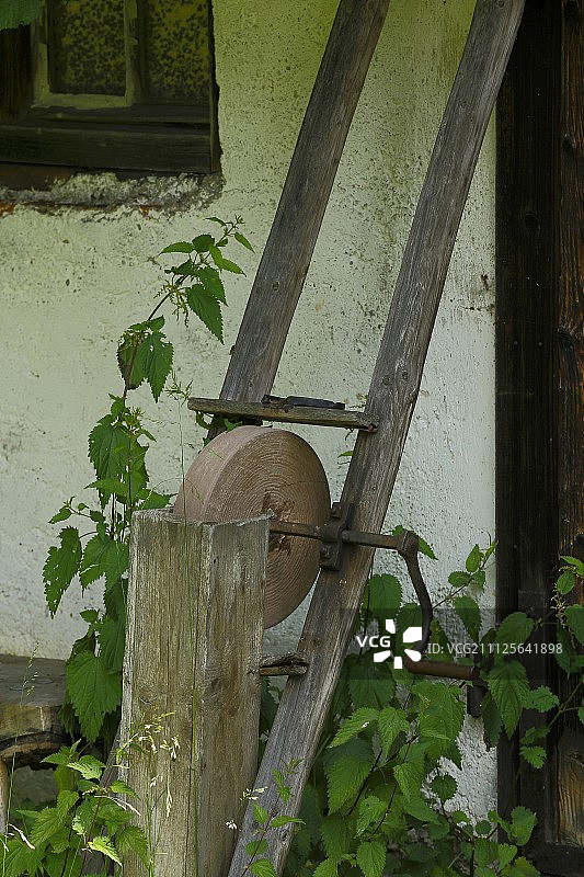 花园里靠在房屋外墙上的旧磨刀石图片素材