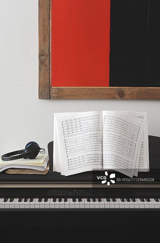 电子钢琴上的乐谱和耳机，下方是黑色和红色现代艺术品图片素材