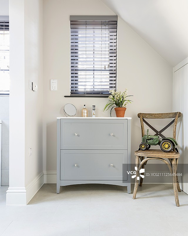 木椅上和抽屉柜旁的玩具，窗户在后图片素材