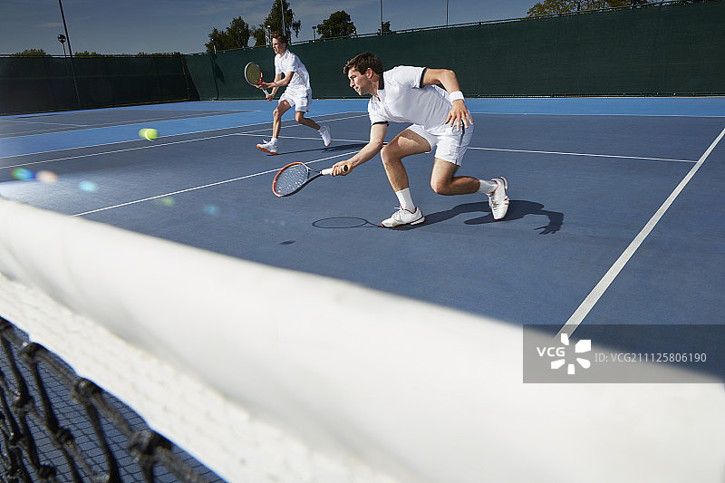年轻的男子网球双打选手在网球场上打网球图片素材