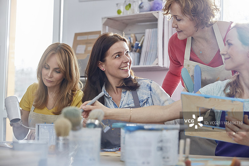 女教师在艺术课工作室帮助学生绘制相框图片素材