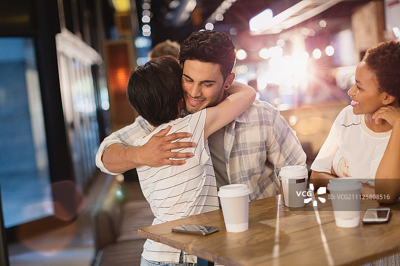 年轻情侣在咖啡馆里拥抱喝咖啡图片素材