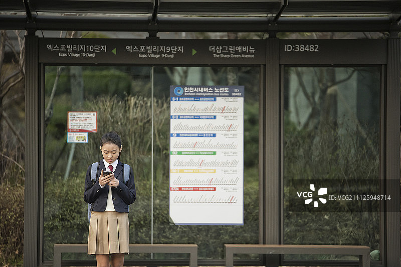 女学生在公交车站等公共汽车图片素材