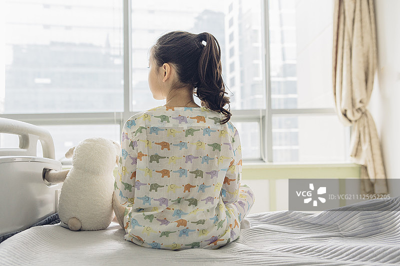 坐在病床上，望着窗外的小女孩图片素材