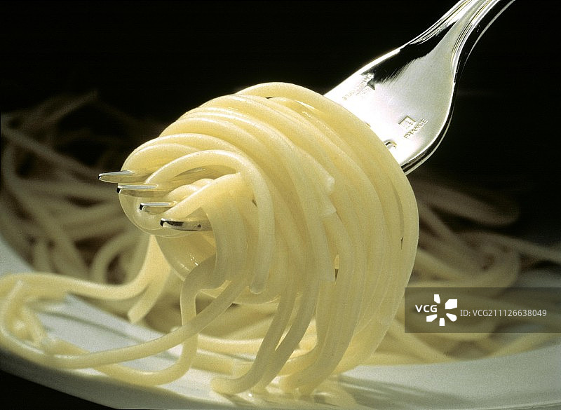 缠绕在叉子上的煮熟的意大利面特写图片素材