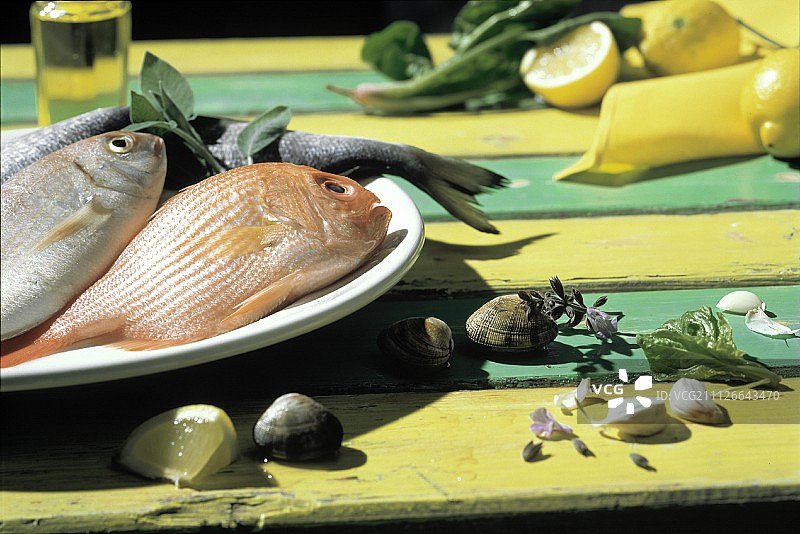 盘中整条鲜鱼、蛤蜊和大蒜瓣图片素材