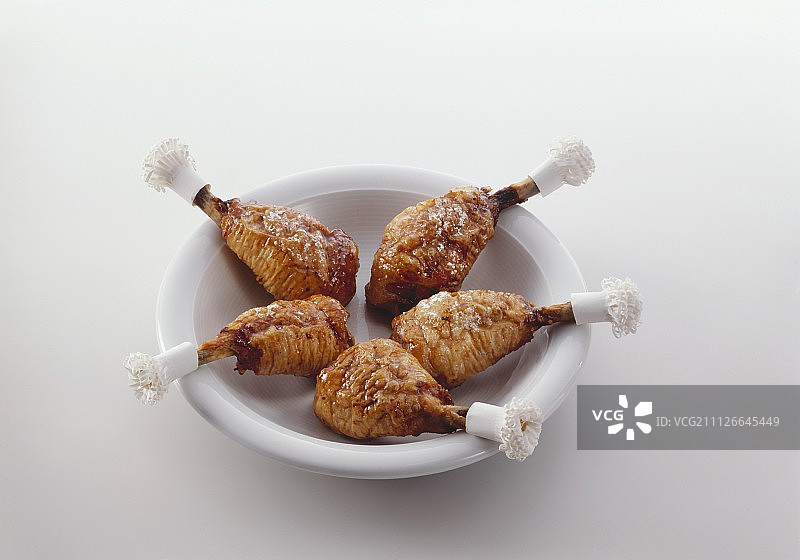 深盘中带纸褶的烤鸡腿图片素材