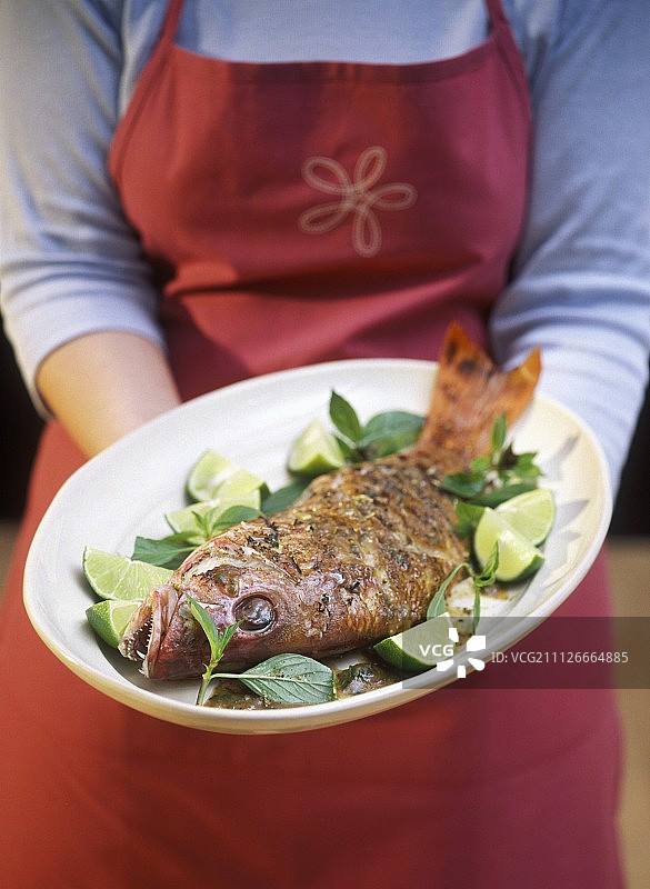 女人拿着烤红鲷鱼拼盘图片素材