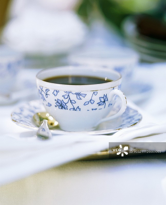 带有蓝色图案的白色瓷杯中的黑咖啡图片素材