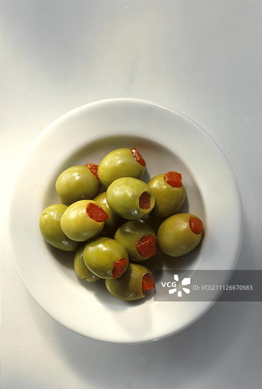酿胡椒的绿色橄榄，在白色盘子上图片素材
