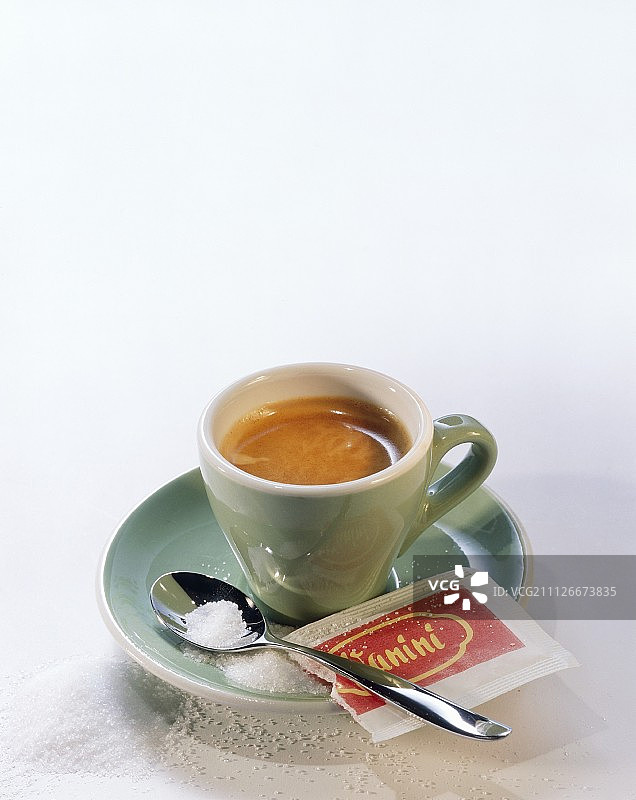 绿杯中的意式浓缩咖啡，配勺子、糖和糖包图片素材