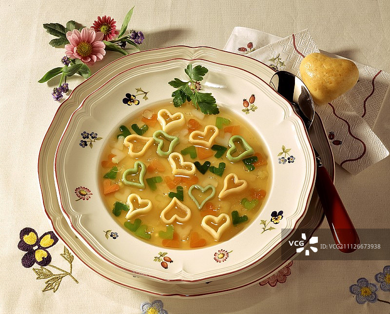 盘子里有蔬菜心形汤，心形面包卷图片素材