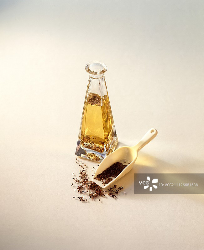 玻璃瓶中的香菜油和小勺子上的香菜图片素材
