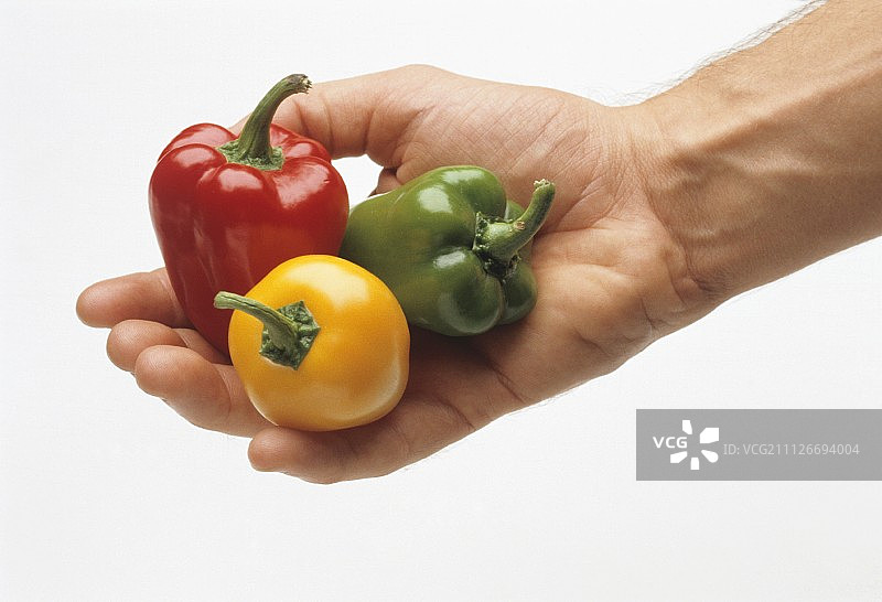 手中的黄色、绿色和红色小辣椒图片素材