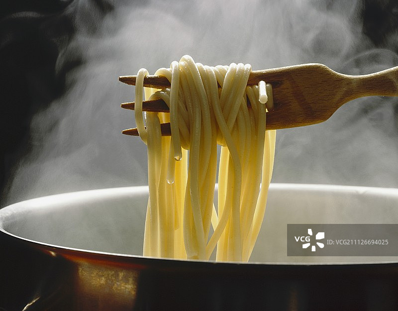 用木叉从热气腾腾的平底锅中挑起意大利面图片素材