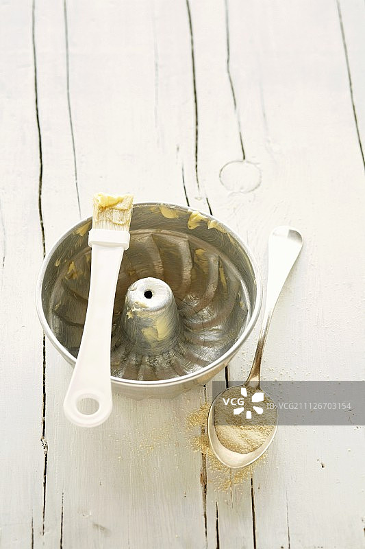 在环形蛋糕罐上涂油并撒上面包屑图片素材