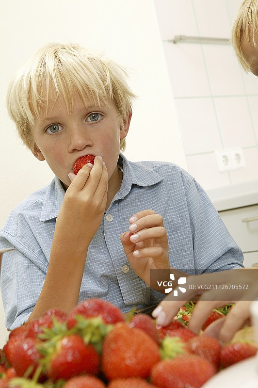 金发男孩咬草莓图片素材
