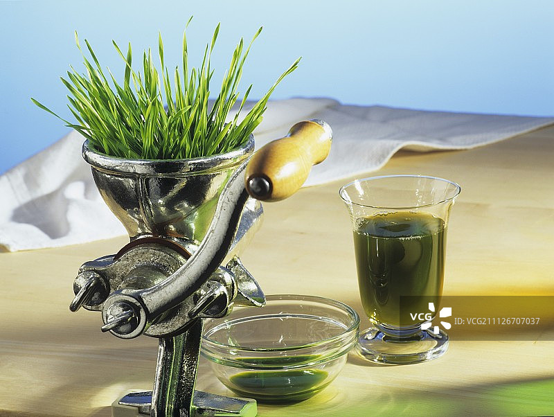 榨汁机中的小麦草和一杯果汁图片素材