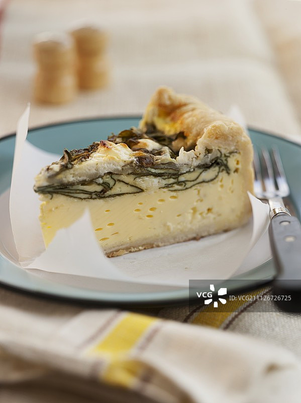 蓝色盘子上的一块菠菜山羊奶酪乳蛋饼图片素材