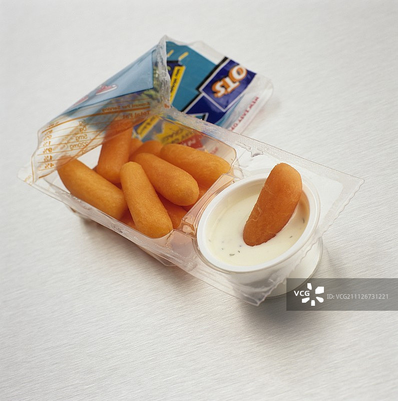 打开的含蘸酱小胡萝卜零食包，胡萝卜蘸入酱中图片素材