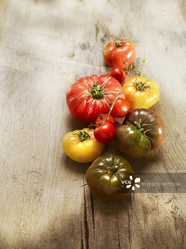 木质表面的各种番茄（克里米亚黑番茄、牛心番茄和菠萝番茄）图片素材