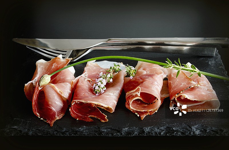 在石板上放着韭菜和卷好的黑森林火腿片图片素材