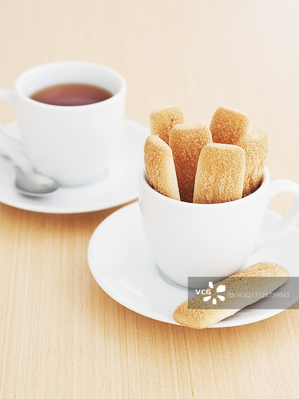 白色杯子里的海绵手指饼干和一杯茶图片素材