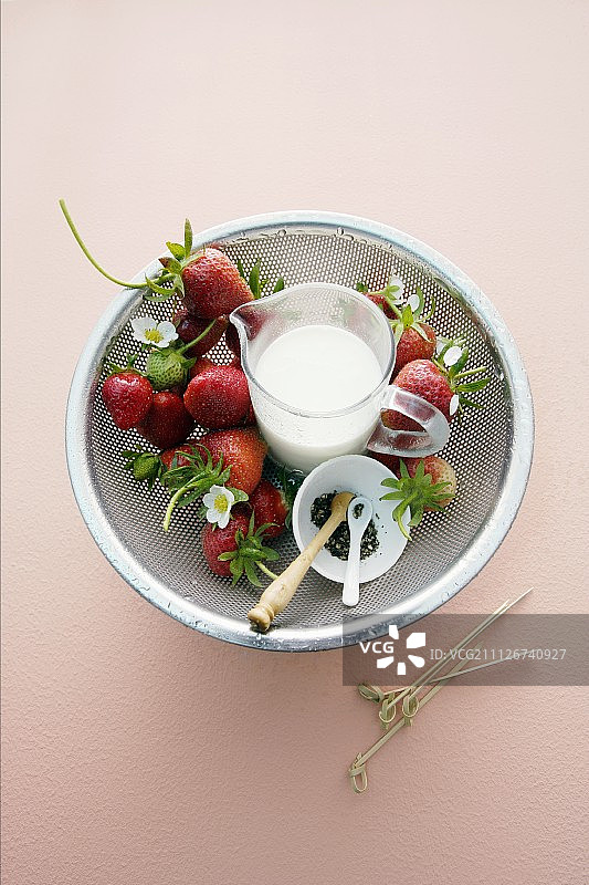 滤水器里的新鲜草莓和一壶牛奶图片素材