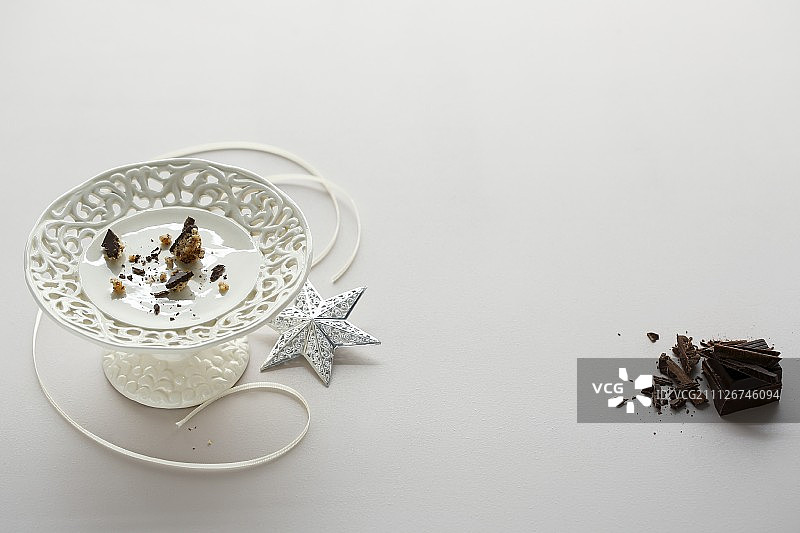 白色蛋糕架上的碎屑、丝带和银色装饰星，左侧有磨碎的巧克力图片素材