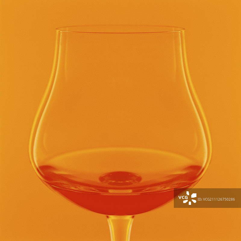 橙色背景下的一杯干邑图片素材