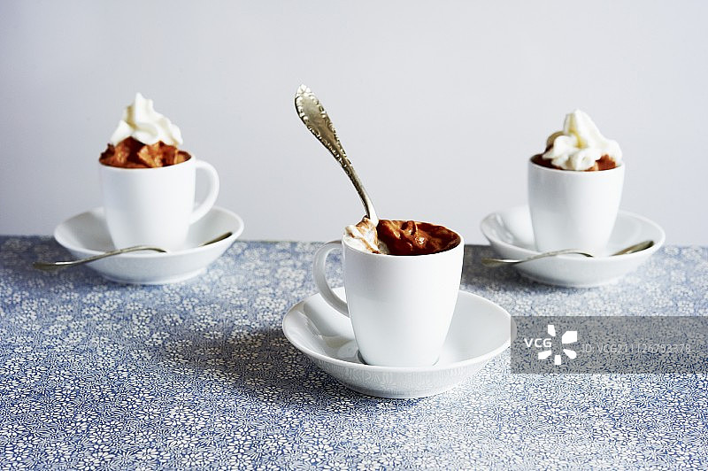 碟子上盛有鲜奶油的杯装巧克力慕斯图片素材