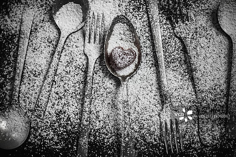 撒满糖粉的餐具，勺子上的心形糖果图片素材