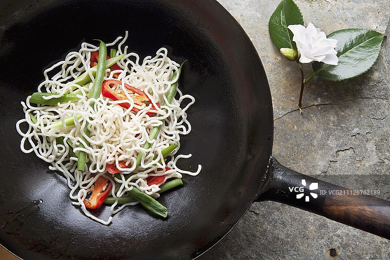 生的蔬菜、辣椒和面条在炒锅中图片素材