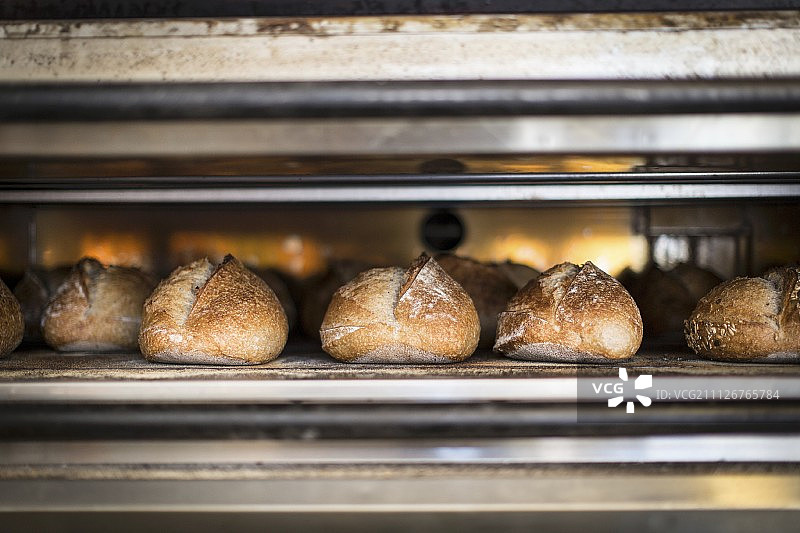 在面包店烤箱中烘烤的白面包图片素材