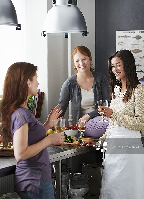 三个朋友在厨房里喝酒图片素材