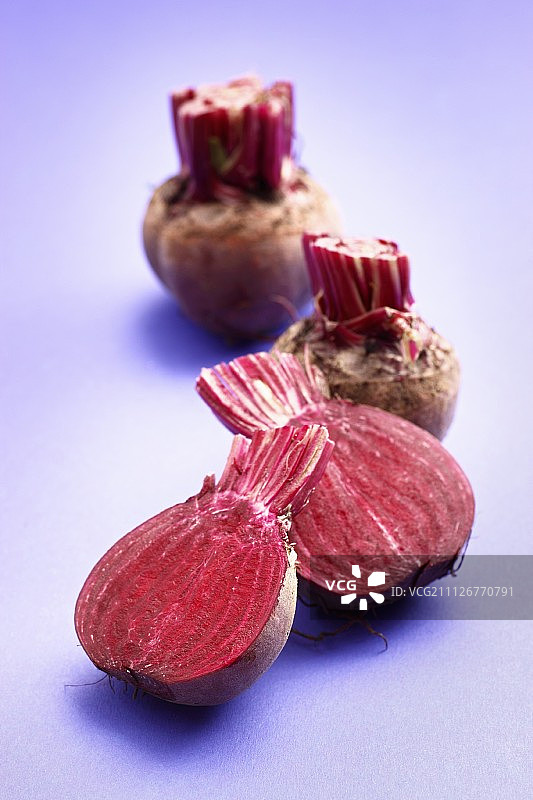 紫色表面上的完整和对半甜菜根图片素材
