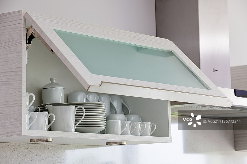 带有开放式推拉门的壁橱，露出白色陶器，旁边是嵌入式不锈钢抽油烟机图片素材