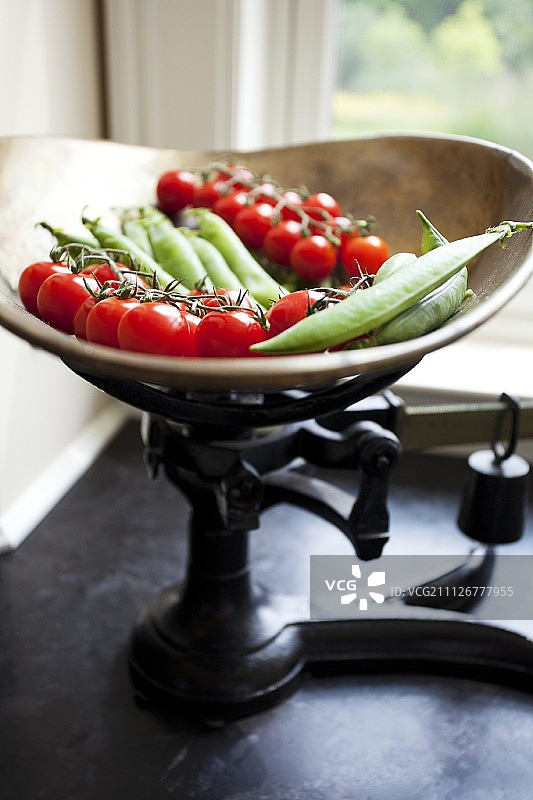旧厨房秤上的圣女果和豌豆荚图片素材