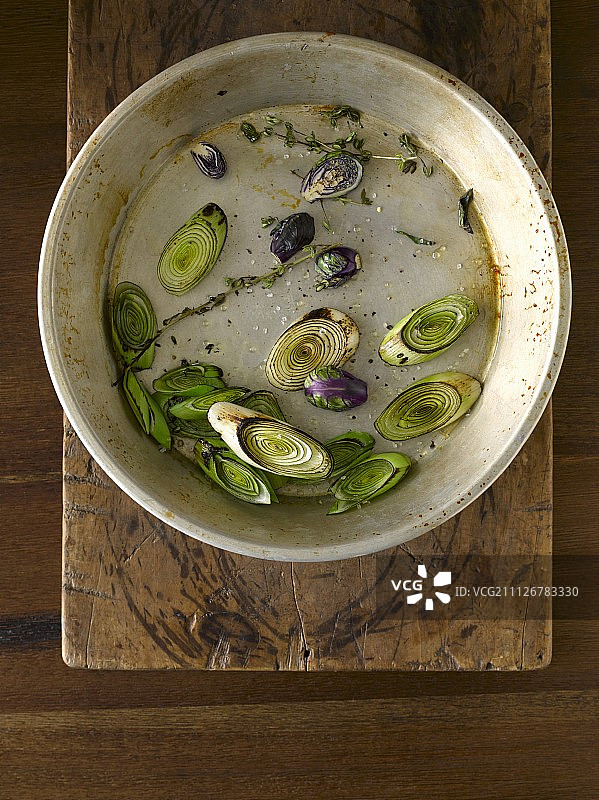 旧馅饼盘中百里香香料烤焦的韭葱和紫色球芽甘蓝片图片素材