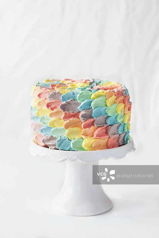 蛋糕架上的彩虹花瓣生日蛋糕图片素材