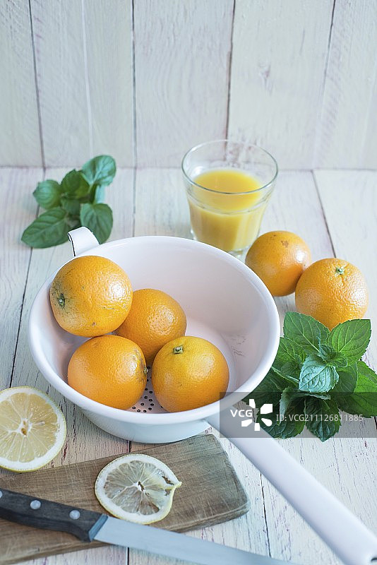 搪瓷漏勺里的橙子、新鲜薄荷、橙汁和柠檬片图片素材