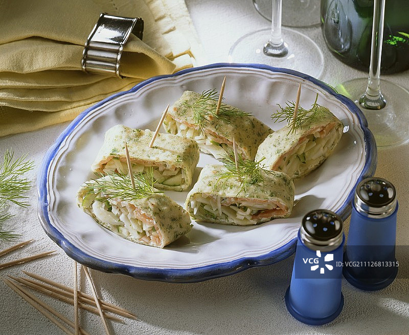 木制鸡尾酒签上的烟熏三文鱼卷切片图片素材