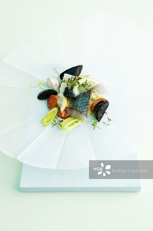 羊皮纸上的鱼和贻贝配韭菜和番茄图片素材