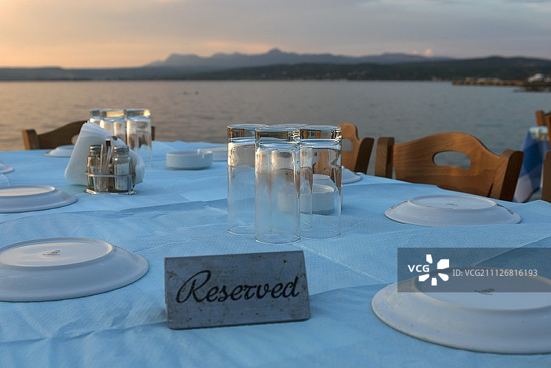 铺着淡蓝色桌布、以希腊海岸为背景的餐桌图片素材
