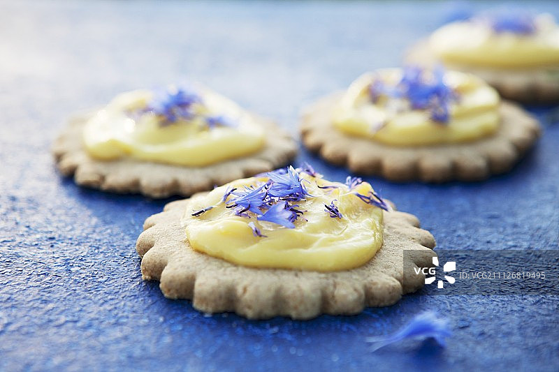 蓝色表面上的柠檬酱和矢车菊酥饼图片素材